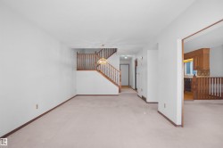 Open-concept living space with light-toned carpeting and white walls - 