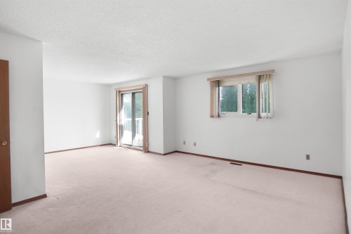 Bright interior space featuring a sliding glass door with balcony access and a secondary window - 12311 25 Avenue Nw, Edmonton, AB 