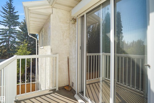 Balcony with white railing, textured stucco exterior, and sliding glass door - 12311 25 Avenue Nw, Edmonton, AB 