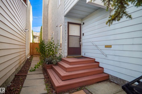 Wood-tone multi-level entry stairs with a handrail, leading to a screen door entry - 12311 25 Avenue Nw, Edmonton, AB 