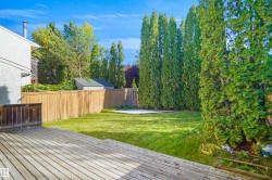 Expansive wood deck with a manicured lawn, established privacy trees, and a wooden fence - 