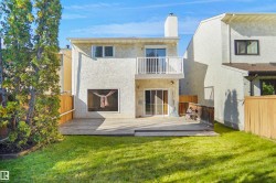 Expansive backyard featuring a large wooden deck, vibrant green lawn, and privacy fencing - 