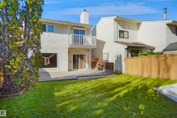 Expansive lawn with a wooden deck, second-story balcony, sliding glass doors, and privacy fencing - 