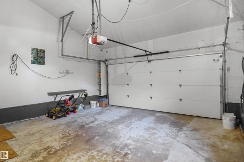 Attached garage with an automatic opener, white sectional door, and built-in shelving - 12311 25 Avenue Nw, Edmonton, AB 