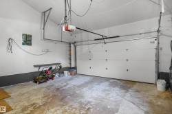 Attached garage with an automatic opener, white sectional door, and built-in shelving - 