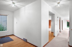 White painted walls, wood-finish flooring, ceiling-mounted light fixtures, and a window with blinds - 