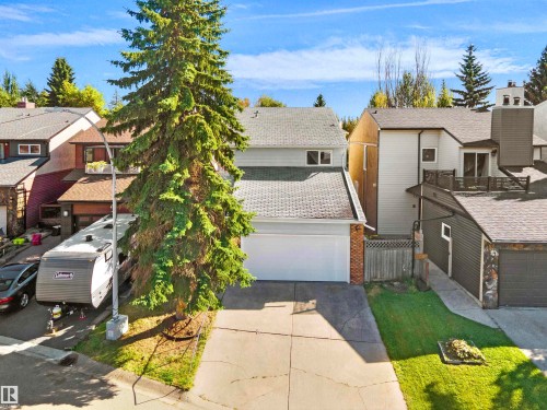 Two-story residence with an attached garage, paved driveway, and mature landscaping - 12311 25 Avenue Nw, Edmonton, AB 