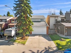 Front exterior featuring a two-car garage, brick accents, and a paved driveway - 