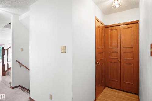 Wood-paneled bi-fold closet doors with natural wood flooring - 12311 25 Avenue Nw, Edmonton, AB 