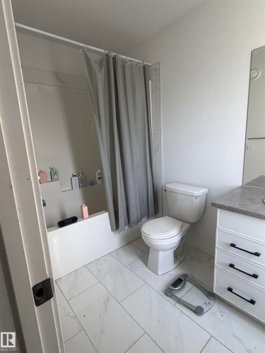 White tiled flooring, white bathtub, white vanity with drawer storage, and a built-in toilet - 11442 82 Street Nw, Edmonton, AB 