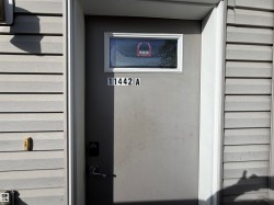 Grey exterior siding with a grey entry door featuring a transom window, modern door hardware, and a digital key pad - 