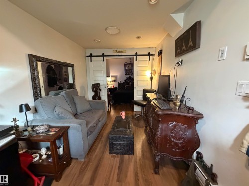 Wood-finish flooring throughout, recessed lighting, and a barn door leading to an additional area - 11442 82 Street Nw, Edmonton, AB 