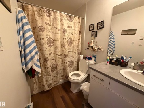 Wood-finish flooring with a vanity featuring a light-toned countertop and integrated sink - 11442 82 Street Nw, Edmonton, AB 