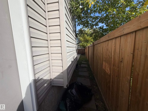 Vinyl siding exterior with a wood privacy fence and a stepping stone pathway - 11442 82 Street Nw, Edmonton, AB 