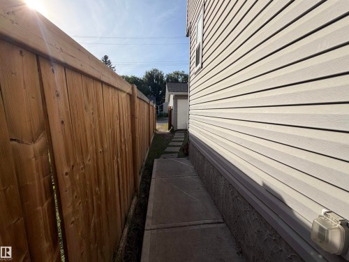 Wood privacy fence and concrete stepping stones alongside siding exterior - 11442 82 Street Nw, Edmonton, AB 
