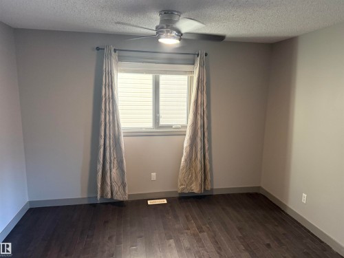 Wood-finish flooring, neutral wall paint, and a ceiling fan with integrated lighting - 7065 Cardinal Way Sw, Edmonton, AB 