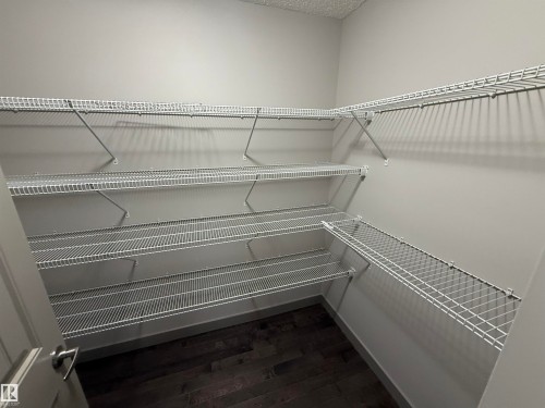 Wrap-around wire shelving with multiple levels, wood-finish flooring, and light gray wall finishes - 7065 Cardinal Way Sw, Edmonton, AB 