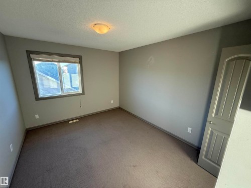 Neutral wall paint, window with blinds, overhead light fixture, carpeted flooring, and a paneled interior door - 7065 Cardinal Way Sw, Edmonton, AB 