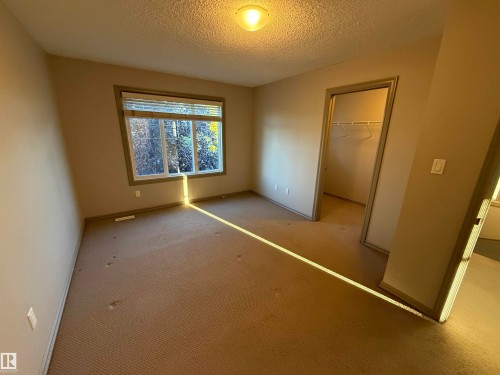 Neutral wall colors, textured ceiling, a window with blinds, and a built-in closet with wire shelving - 7065 Cardinal Way Sw, Edmonton, AB 