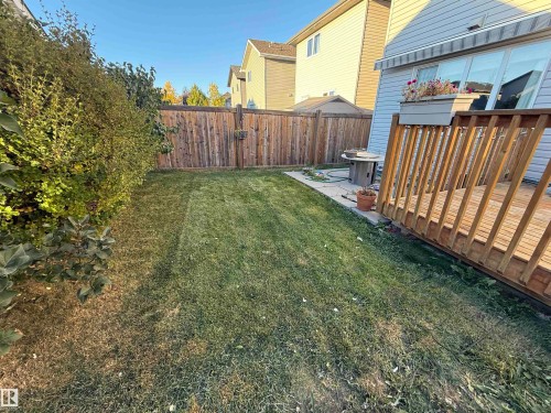 Expansive backyard featuring a wood privacy fence, a wood deck, and a concrete patio area - 7065 Cardinal Way Sw, Edmonton, AB 