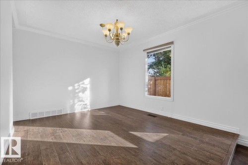 Wood-finish flooring, crown molding, and a chandelier with glass shades - 8 Wahstao Crescent Nw, Edmonton, AB 