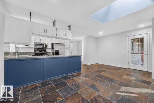 Kitchen area with dark slate-style flooring, white upper cabinetry, and blue lower cabinetry - 8 Wahstao Crescent Nw, Edmonton, AB 