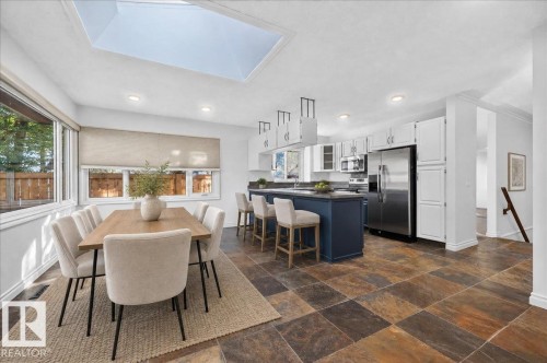 Spacious kitchen with a central island, white cabinetry, integrated stainless steel appliances, and multi-toned tile flooring - 8 Wahstao Crescent Nw, Edmonton, AB 