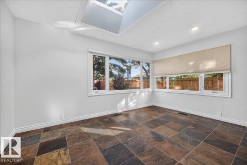 Skylight and recessed lighting illuminate an interior space featuring multi-toned tile flooring - 8 Wahstao Crescent Nw, Edmonton, AB 