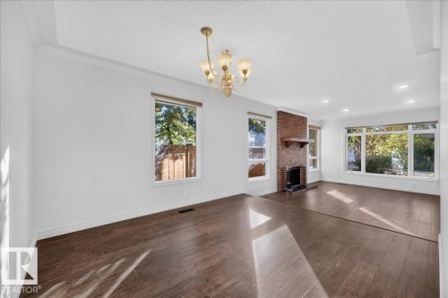 Hardwood-finish flooring throughout, crown molding, brick fireplace with a wood mantle, recessed lighting, and a multi-pane window configuration - 8 Wahstao Crescent Nw, Edmonton, AB 