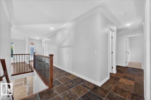 Upper-level landing featuring square-cut tile flooring, crown molding, recessed lighting, and wood newel posts with iron balusters - 8 Wahstao Crescent Nw, Edmonton, AB 