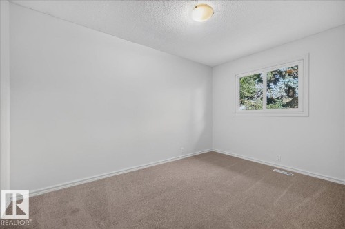 Neutral painted walls, carpeted flooring, and a single window with exterior landscaping - 8 Wahstao Crescent Nw, Edmonton, AB 