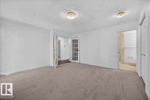 Neutral-toned carpeting throughout, two sets of double French doors, and two flush-mount ceiling light fixtures - 8 Wahstao Crescent Nw, Edmonton, AB 