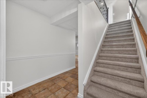 Tiled flooring, wainscoting, and carpeted stairs with a wrought iron and wood handrail - 8 Wahstao Crescent Nw, Edmonton, AB 