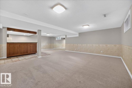 Spacious room with carpet flooring, a built-in wooden bar with countertop, and recessed lighting - 8 Wahstao Crescent Nw, Edmonton, AB 