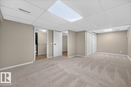 Spacious room with neutral carpeting, drop ceiling, recessed lighting, and bi-fold closet doors - 8 Wahstao Crescent Nw, Edmonton, AB 