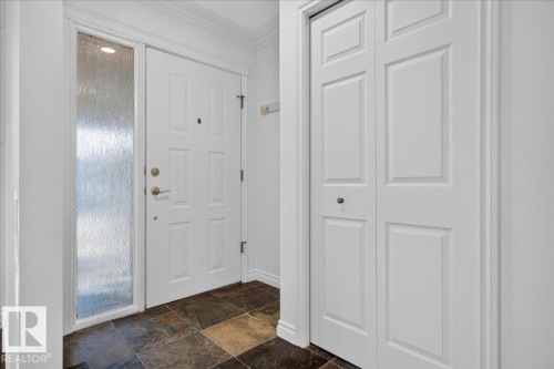 Entryway featuring slate tile flooring, a white paneled door with a textured glass sidelight, and a bi-fold closet with panel detailing - 8 Wahstao Crescent Nw, Edmonton, AB 