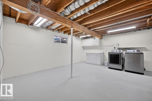 Utility Room with exposed wood joists, concrete flooring, and a laundry area with white cabinetry - 8 Wahstao Crescent Nw, Edmonton, AB 