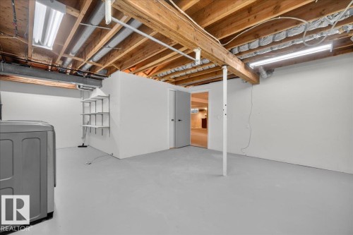 Expansive unfinished basement featuring exposed wood joists, painted concrete flooring, and built-in shelving - 8 Wahstao Crescent Nw, Edmonton, AB 