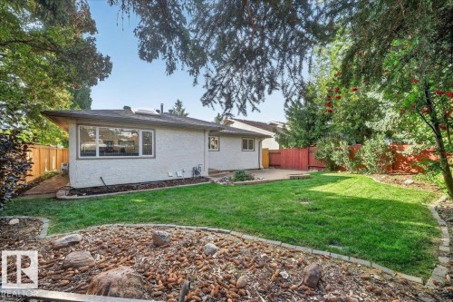 Expansive backyard featuring a manicured lawn, a paved patio, and mature trees providing natural shade - 8 Wahstao Crescent Nw, Edmonton, AB 