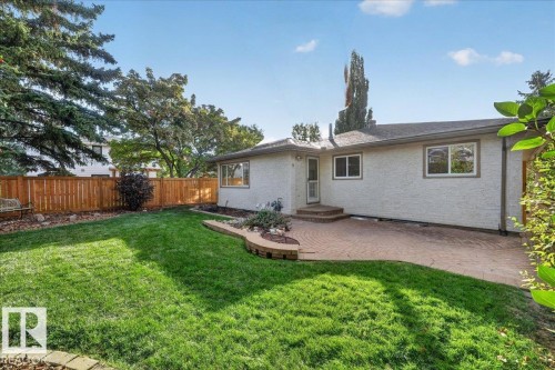 Expansive backyard featuring a paved patio, a wood privacy fence, and mature trees - 8 Wahstao Crescent Nw, Edmonton, AB 