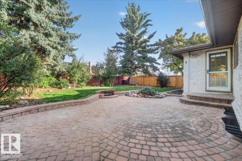 Expansive paver patio with a circular pattern, fire pit, and stone retaining walls - 8 Wahstao Crescent Nw, Edmonton, AB 