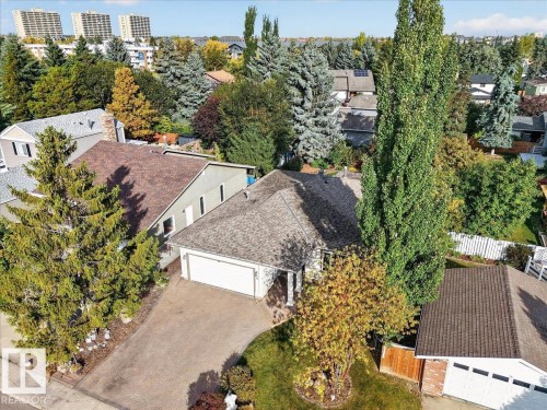 Asphalt shingle roof, attached garage, paved driveway, mature trees, and established landscaping - 8 Wahstao Crescent Nw, Edmonton, AB 