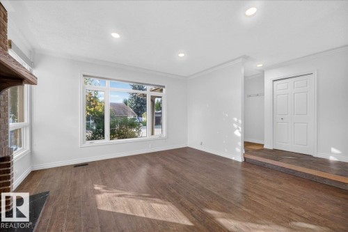 Bright, open living space featuring hardwood flooring, recessed ceiling lighting, and expansive windows framing natural landscape vistas - 8 Wahstao Crescent Nw, Edmonton, AB 
