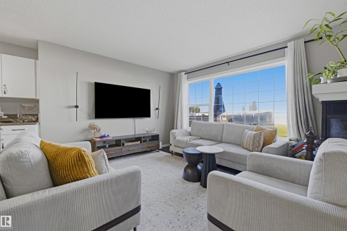 Expansive window offering abundant natural light, recessed lighting, and a built-in fireplace with a mantel - 3151 Trelle Loop Nw, Edmonton, AB 
