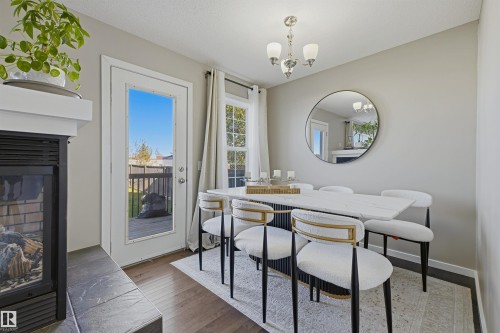 Fireplace with brick interior and tile hearth, glass-paneled door, and wood-finish flooring - 3151 Trelle Loop Nw, Edmonton, AB 
