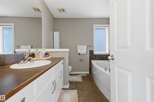 White vanity with ample storage, integrated sink, and an expansive mirror - 3151 Trelle Loop Nw, Edmonton, AB 