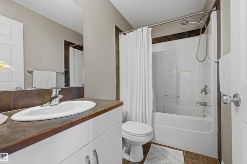 White vanity with integrated sink, dark wood-finish countertop, and full-width mirror - 3151 Trelle Loop Nw, Edmonton, AB 