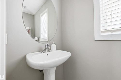 Pedestal sink with chrome faucet, complemented by a round wall-mounted mirror - 3151 Trelle Loop Nw, Edmonton, AB 