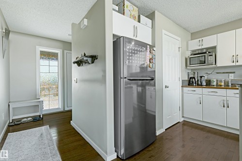 Kitchen area featuring white cabinetry, a built-in microwave, and wood-finish flooring - 3151 Trelle Loop Nw, Edmonton, AB 