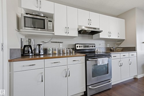 White cabinetry, stainless steel appliances, wood-finish countertops, and wood-finish flooring - 3151 Trelle Loop Nw, Edmonton, AB 
